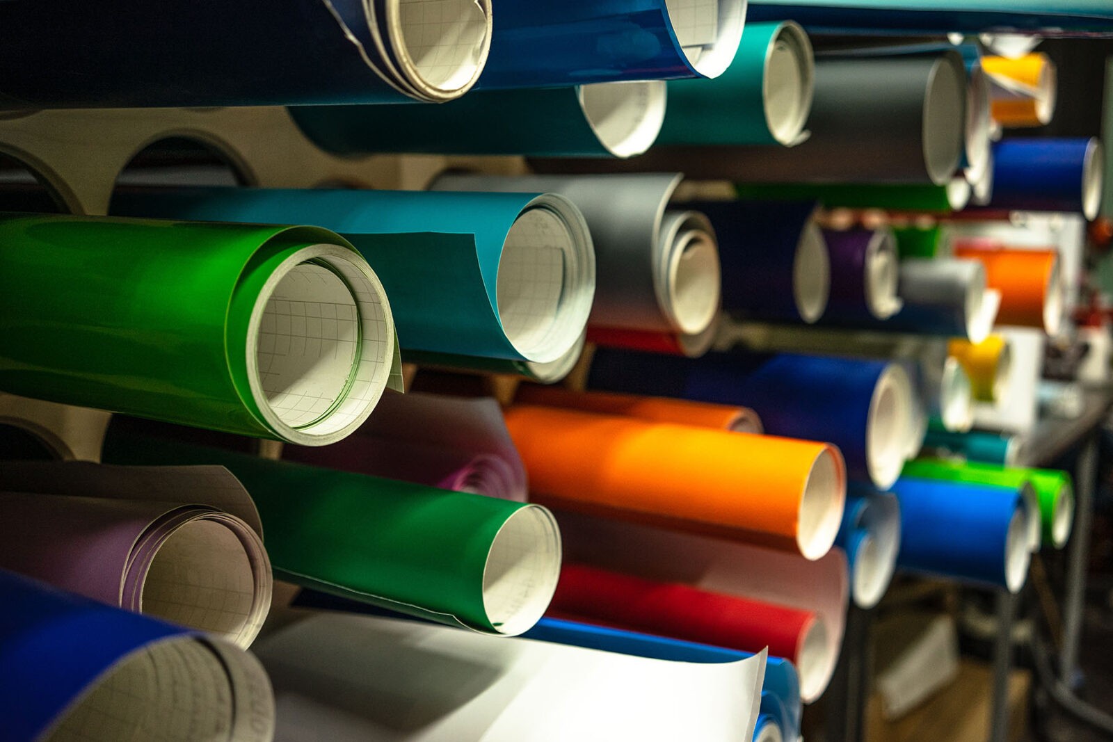 Rolls of heat transfer vinyl in multiple colors sit in a workshop.